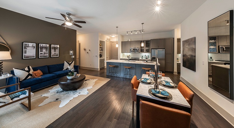 a living room and kitchen area with a blue couch at The Ash at Branch