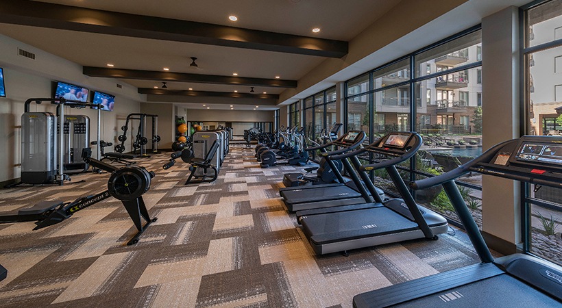 a gym with tread machines and windows overlooking the city at The Ash at  Branch