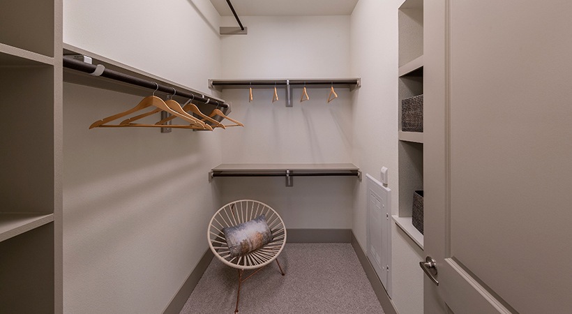 a walk in closet with shelves and a chair at The Ash at  Branch